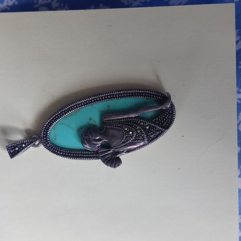 A turquoise and sparkly lady. Art deco. Dressed in a low cut dress, with a fan.